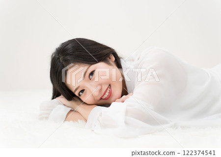 美女形象：穿著白襯衫、微笑著躺著的年輕女子 122374541