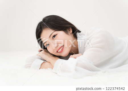 美女形象：穿著白襯衫、微笑著躺著的年輕女子 122374542