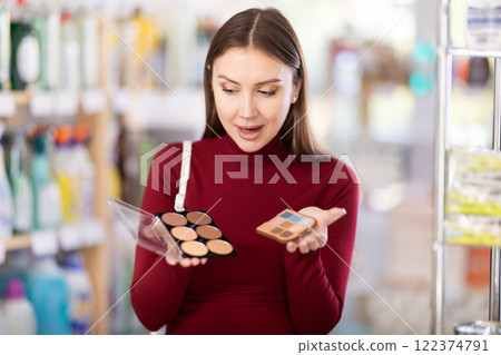 Young woman choosing eyeshadow and sculptor in store Young woman choosing eyeshadow and sculptor in store 122374791