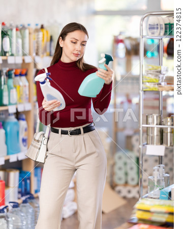 Young woman chooses cleaning spray in store 122374815