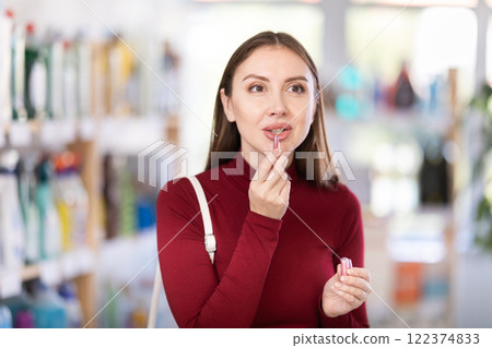 Young woman chooses lipstick sample in store Young woman chooses lipstick sample in store 122374833