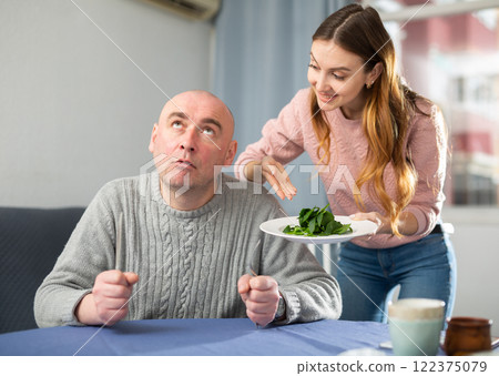 Portrait of a disgruntled man, to whom a young woman brought a plate of spinach Portrait of a disgruntled man, to whom a young woman brought a plate of spinach 122375079