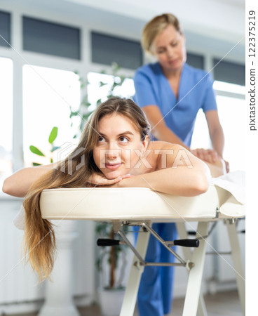 Young woman enjoying massage from professional female masseur Young woman enjoying massage from professional female masseur 122375219