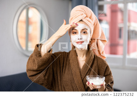 Happy woman taking care of face skin with lotion Happy woman taking care of face skin with lotion 122375232