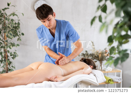 Massage by man in blue scrubs Massage by man in blue scrubs 122375273
