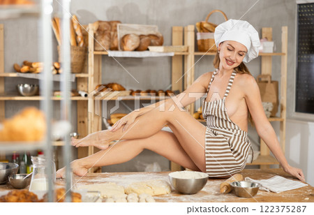 Woman in apron sitting on table in bakery 122375287