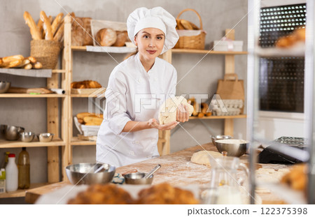 Female baker kneading dough in artisan bakery shop Female baker kneading dough in artisan bakery shop 122375398