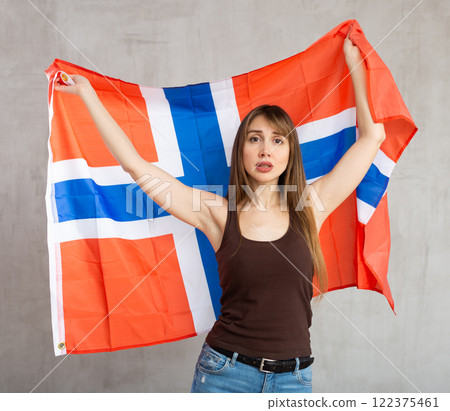 Sad young woman holding flag of Norway against unicoloured background Sad young woman holding flag of Norway against unicoloured background 122375461