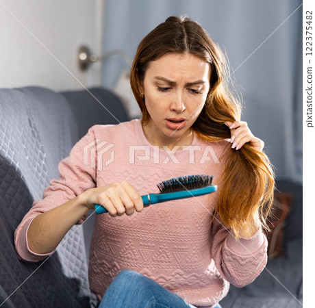 Frustrated young woman combs her hair Frustrated young woman combs her hair 122375482