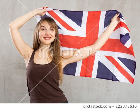 Happy young woman holding flag of Great Britain against unicoloured background 122375630