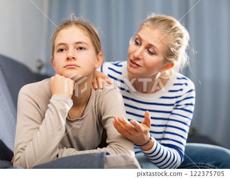 Sad female and daughter sitting at sofa and having quarrel Sad female and daughter sitting at sofa and having quarrel 122375705