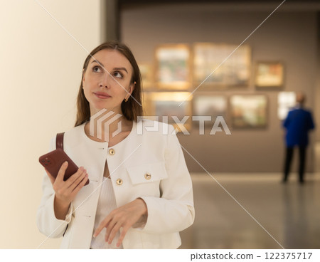 While visiting museum, girl uses travel guide application on her phone. 122375717