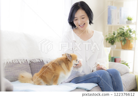 Middle-aged woman relaxing with pet dog Middle-aged woman relaxing with pet dog 122376612