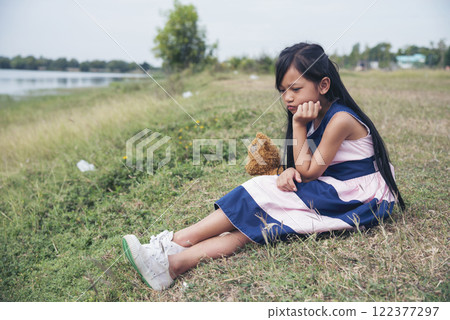 Sad girl hugging teddy bear sadness alone in green garden park. Lonely girl feeling sad unhappy sitting outdoors with best friend toy. Autism child play teddy bear best friend. Family violence concept Sad girl hugging teddy bear sadness alone in green garden park. Lonely girl feeling sad unhappy sitting outdoors with best friend toy. Autism child play teddy bear best friend. Family violence concept 122377297