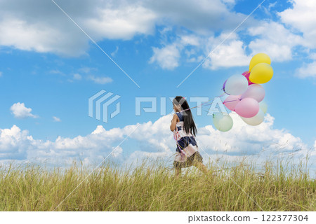 Cheerful beauty woman holding balloons relax sitting under big tree in green park with happiness. Woman Hands holding vibrant air balloons play on birthday party happy time summer on sunshine outdoor Cheerful beauty woman holding balloons relax sitting under big tree in green park with happiness. Woman Hands holding vibrant air balloons play on birthday party happy time summer on sunshine outdoor 122377304