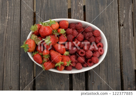 raspberries and strawberries, red berries, in a plate on a dark wooden background raspberries and strawberries, red berries, in a plate on a dark wooden background 122377885