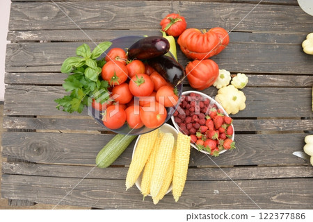 harvested vegetables. Tomatoes, corn, berries, eggplant on a wooden dark background harvested vegetables. Tomatoes, corn, berries, eggplant on a wooden dark background 122377886