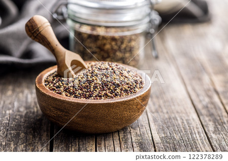 Mixed uncooked quinoa seeds in bowl on wooden table. 122378289
