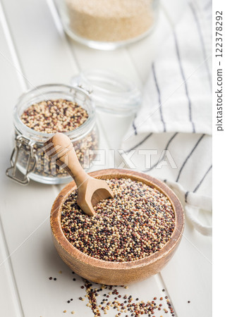 Mixed uncooked quinoa seeds in bowl on white table. 122378292