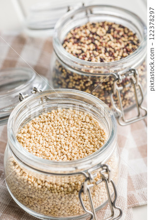 Mixed uncooked quinoa seeds in jar on checkered napkin 122378297
