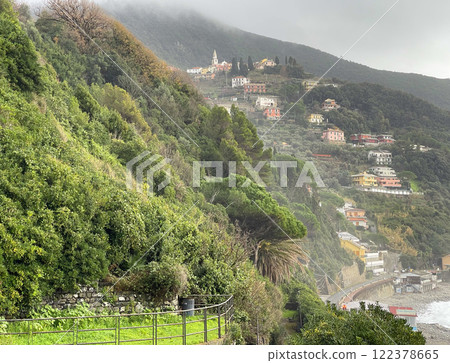 Moneglia, Italy - 09 January 2025. Old park by sea. Overcast weather, fog. Plant and tree. Stone wall, building in Italy. Municipality of Moneglia, Liguria region. View from mountain.  122378665