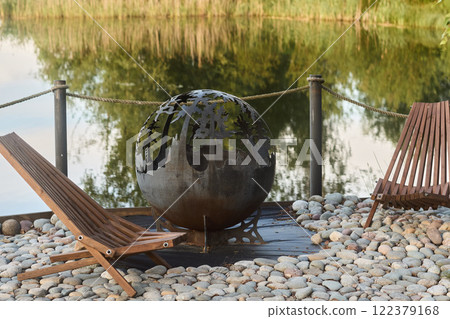 Experience the serene and artistic Outdoor Art Sphere nestled by the tranquil waterside 122379168