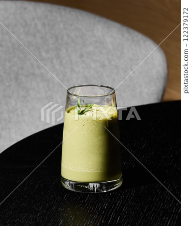 A Refreshing Green Smoothie Served in a Glass Resting Beautifully on a Table Surface A Refreshing Green Smoothie Served in a Glass Resting Beautifully on a Table Surface 122379172
