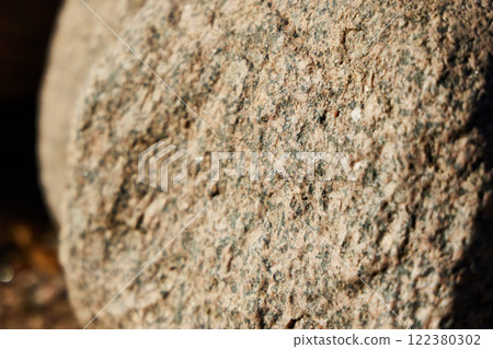 A closeup view of a rough stone surface illuminated by natural light, highlighting its texture 122380302