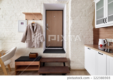 A Modern Apartment Entry Featuring a WellDesigned Kitchen and a Chic Coat Rack Display 122380303
