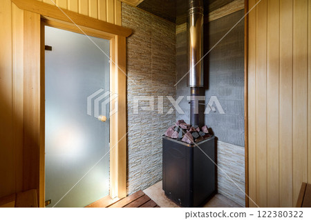 A Cozy and Inviting Sauna Interior Featuring a Beautiful Stone Wall and a Heater for Comfort 122380322