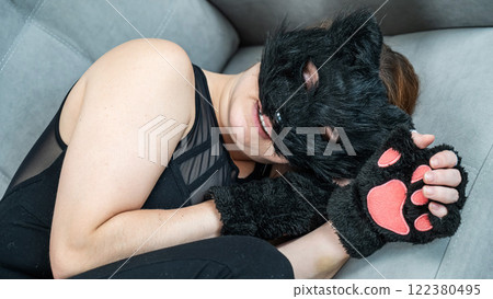 A woman in a cat costume lies on a gray sofa. Quadrober. A woman in a cat costume lies on a gray sofa. Quadrober. 122380495