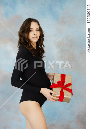 Elegant woman in black holding a gift box 122380541