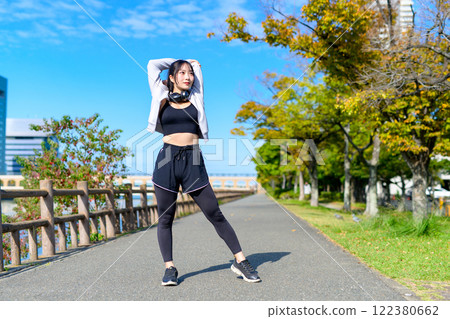Shoulder blade stretching: Cool woman stretching her shoulders outdoors, diet, walking, exercise 122380662