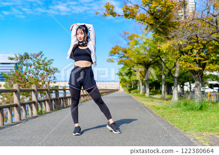 Shoulder blade stretching: Cool woman stretching her shoulders outdoors, diet, walking, exercise 122380664