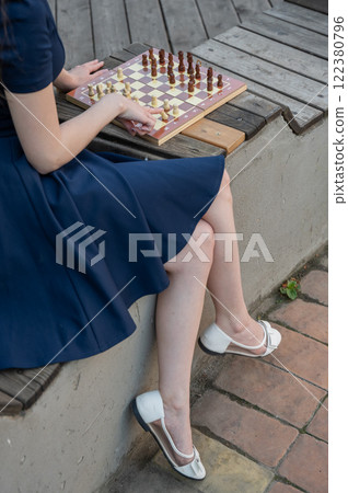 Caucasian woman playing chess outdoors. Caucasian woman playing chess outdoors. 122380796