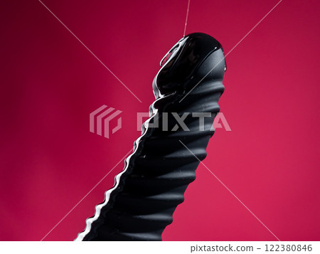 Lube pouring on black dildo on pink background. Lube pouring on black dildo on pink background. 122380846