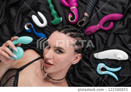 Portrait of Caucasian woman lying on bed among sex toys.  122380855