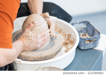 Close-up of a potter's hands working on a pottery wheel.  122380902