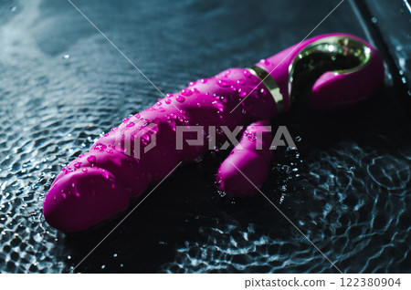 Pink ribbed vibrator in water. Circles on water around sex toy.  122380904