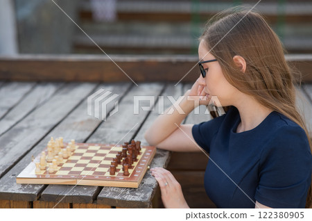 Caucasian woman playing chess outdoors.  122380905