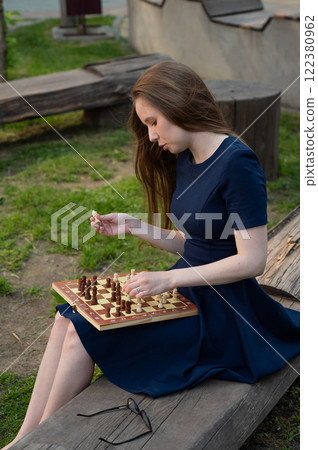 Caucasian woman playing chess outdoors. Caucasian woman playing chess outdoors. 122380962
