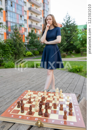 Caucasian woman playing chess outdoors. Caucasian woman playing chess outdoors. 122381010