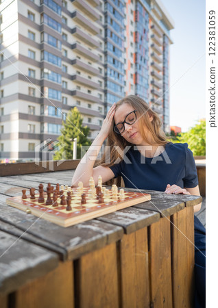 Caucasian woman playing chess outdoors. Vertical photo.  122381059