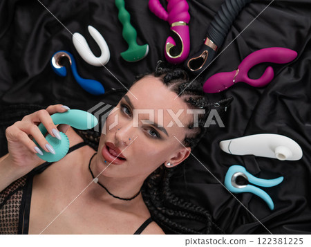 Portrait of Caucasian woman lying on bed among sex toys. Portrait of Caucasian woman lying on bed among sex toys. 122381225