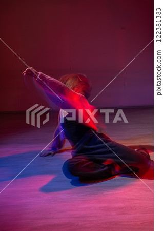 A young woman dances contemporary dances in blue and red light. Long exposure. Vertical photo. A young woman dances contemporary dances in blue and red light. Long exposure. Vertical photo. 122381383