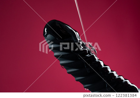 Lube pouring on black dildo on pink background.  122381384