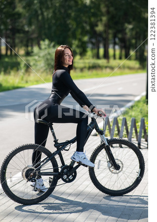 Rear view of Caucasian woman riding bike in park. Vertical photo. Rear view of Caucasian woman riding bike in park. Vertical photo. 122381394