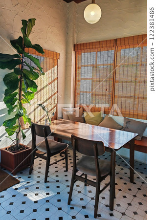 restaurant table and chairs  by tree and natural light from window 122381486