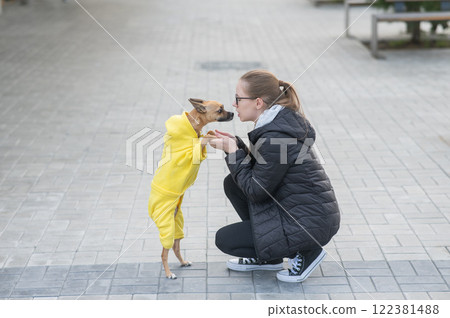 Young Caucasian woman kissing her small dog on a walk.  122381488