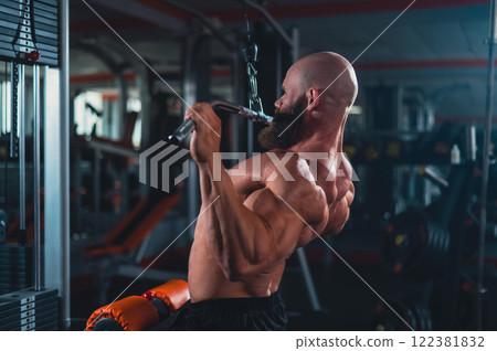 Caucasian man doing lat pull-downs on a machine. Caucasian man doing lat pull-downs on a machine. 122381832